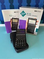 HP 48S calculator with original box, user manual, and black zippered case all displayed on table.