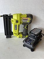 Ryobi cordless AirStrike brad nailer with battery charger, front view.