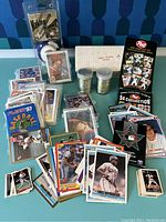 Photo shows multiple stacks and loose baseball cards from various brands alongside two plastic tubes filled with coins and boxes labeled '1987 Topps Coins'. Cards include player images and team logos.