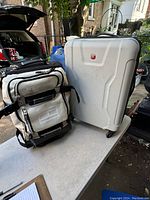 Photo of both travel suitcases on a table outside, showing the Tommy Hilfiger soft suitcase and Swiss Gear hard suitcase side by side
