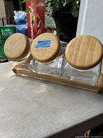 Top view of three glass canisters with round wooden lids, arranged on a wooden rack.