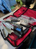 Overview of the seven cutting instruments inside a red and black nylon carrying case, showing handles and blade sheaths.