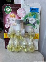 Front view of the Air Wick Life Scents plug-in warmer pack showing four plug-in warmers and nine refill bottles of scented oil. The box is labeled with scent descriptions and usage instructions.