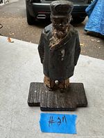Front view of the cast iron door stopper showing the figure of a man in coat and hat on its base with paint wear