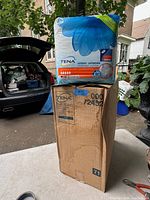 Photo showing 4 packs of TENA unisex underwear stacked on a brown box with blue writing and sticker #39 x 48
