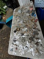 Wide view of large assortment of costume jewelry on table, many pieces individually bagged showing variety.