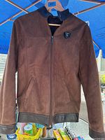 Full view of the men's brown suede and leather jacket, showing front zipper, pockets, and leather collar, cuffs and waistband accents.
