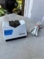 White Philips electric cutting instrument sharpener with black sharpening sections and power cord.