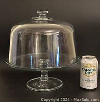 Heavy clear glass round cake stand with dome lid, shown next to a 355 ml Canada Dry Diet Ginger Ale can for scale.