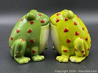 Two ceramic frogs facing each other with red heart decorations, showing texture, color, and design for salt and pepper shakers.