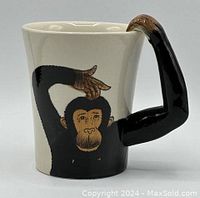 Front view showing monkey face and arm-shaped handle painted black with brown hand on the top rim.