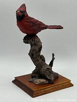 Front view of red cardinal statue perched on branch, showing details of bird and base.