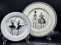 Two plates displayed on stands; smaller white skeleton ballerina plate on the left and larger cream skeleton couple plate on the right.