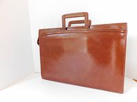 Side view of brown leather briefcase showing supple grain texture and retractable handle