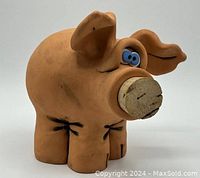 Side view of vintage clay piggybank showing blue eyes, cork nose, and ear detail.