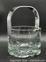 Front view of the clear thick crystal ice bucket with silver tone metal handle, showing rounded sides and flower swirl pattern in the crystal base.