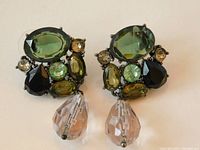 Pair of vintage Schreiner japanned metal drop earrings showing clusters of multi-shaped stones in green, aqua, black, and clear colors with faceted clear pear drop.