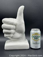 Front view of white ceramic thumbs up hand sculpture with a Canada Dry can for size reference.