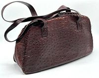 Side angle showing distinctive bumpy ostrich leather texture with double straps and zip closure.