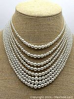 Front view of the 8-strand graduated faux pearl necklace displayed on a mannequin, showing the elegant layering and size variation of the pearls.