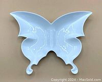 Top view of the white ceramic butterfly-shaped plate showing butterfly wing contours and curled ends.