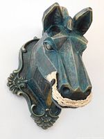Front view of geometric hunter green horse head wall sculpture with detailed carved eyes and braided rope mouth guard attached.