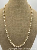 Front view of knotted faux pearl necklace displaying round uniform faux pearls, arranged on a bust form for scale and presentation.
