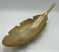Top view of large leaf-shaped brass bowl platter on white background