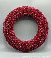 Front view of the bright red artificial berry wreath on a plain background.