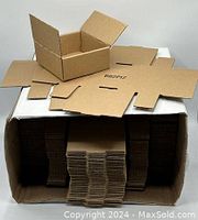 Top view showing several flat unassembled cardboard boxes stacked inside a larger box, with one partially assembled box on top showcasing size and shape.