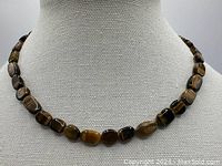 Front view of tiger's eye necklace displayed on bust showing bead shape and clasp