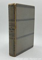 Front and spine view of the vintage hardcover book with worn spine and gray cover with black decorative lines.
