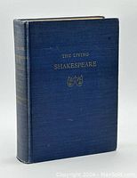 Front angled view of vintage hardcover book The Living Shakespeare showing blue cloth cover with gold title and theater masks.