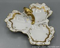 Top view showing the three divided compartments with scalloped edges and gold trim, with ornate gold handle in center