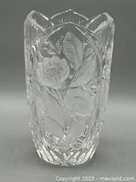 Front view of heavy ornate clear crystal vase with frosted floral and leaf designs and leaf-shaped scalloped rim