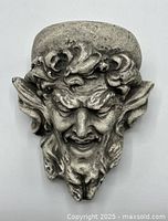 Front view of grey plaster satyr head wall shelf with detailed facial features and curly hair.