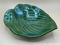 Top view of glossy green ceramic platter shaped like a leaf, showing detailed vein work and curved edges