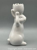 Side view of white ceramic rabbit-shaped vase holding an egg-shaped top with scalloped rim.
