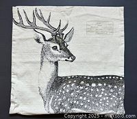 Front view of cream colored pillow cover with detailed black deer illustration and label print in upper right corner.