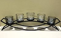 Front view of the assembled double arch black metal candle holder with five glass holders (3 smoked, 2 clear) placed in position.