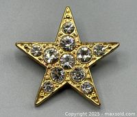 Front view of the gold-toned star-shaped brooch with clear rhinestones, showing design and condition.