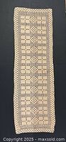 Full view of beige crocheted table runner laid flat showing rectangular shape and pattern.
