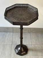 Full view of the vintage octagonal metal table showing embossed decorative top and pierced rim.