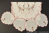Full view of vintage white fabric table runner and four round doilies arranged around it, showing scalloped edges and embroidered strawberry design
