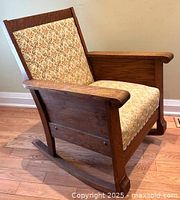 Side view of vintage oak rocking chair showing wooden frame, upholstered seat and back, and the rocking base.