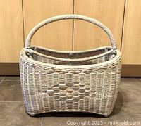 Front view of the wicker magazine rack showing the woven pattern, handle, and overall structure.