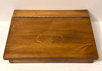 Top view of wood lap desk showing golden brown wood and gold swirl decorative design on hinged lid.