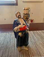 Front view of porcelain vodka decanter shaped as a Hetman holding a small barrel with gold trim.