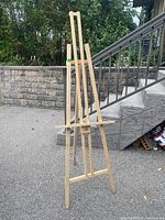 Front view of the wooden artist easel standing upright outdoors showing the adjustable canvas support and height.