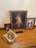All three framed religious artworks shown upright against a wall with beige religious printed bag in front on floor